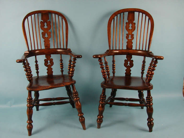 A pair of English broad arm Windsor arm chairs with Christmas tree splats  and well-turned supports, the hickory seats  supported by turned legs joined by double 