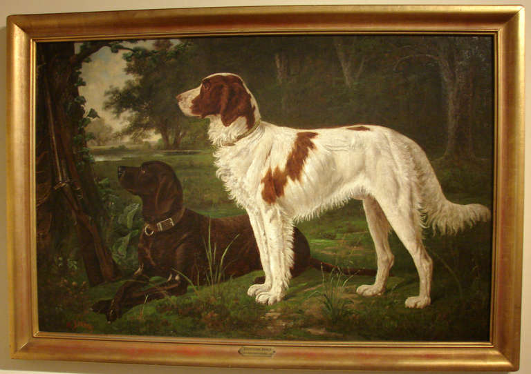 A well-executed oil on canvas in a gilt frame depicting an Irish Red and White setter and another hunting dog in an English forest setting with a lake in the background, a shotgun propped up against a tree trunk. Signed lower left 