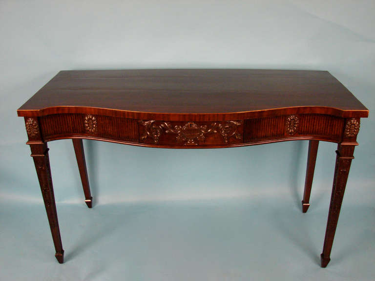 A handsome, good quality English mahogany Adam style serpentine console table, the boxwood edged top above a carved frieze with a highly carved center drawer, all supported on carved square tapered legs ending in spade feet,
circa 1890.