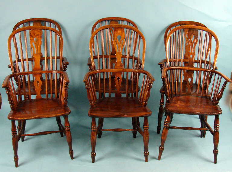 An assembled set of 6 English elm and hickory high back Windsor arm chairs of typical form, all with attractive color the hickory seats above turned legs joined by 