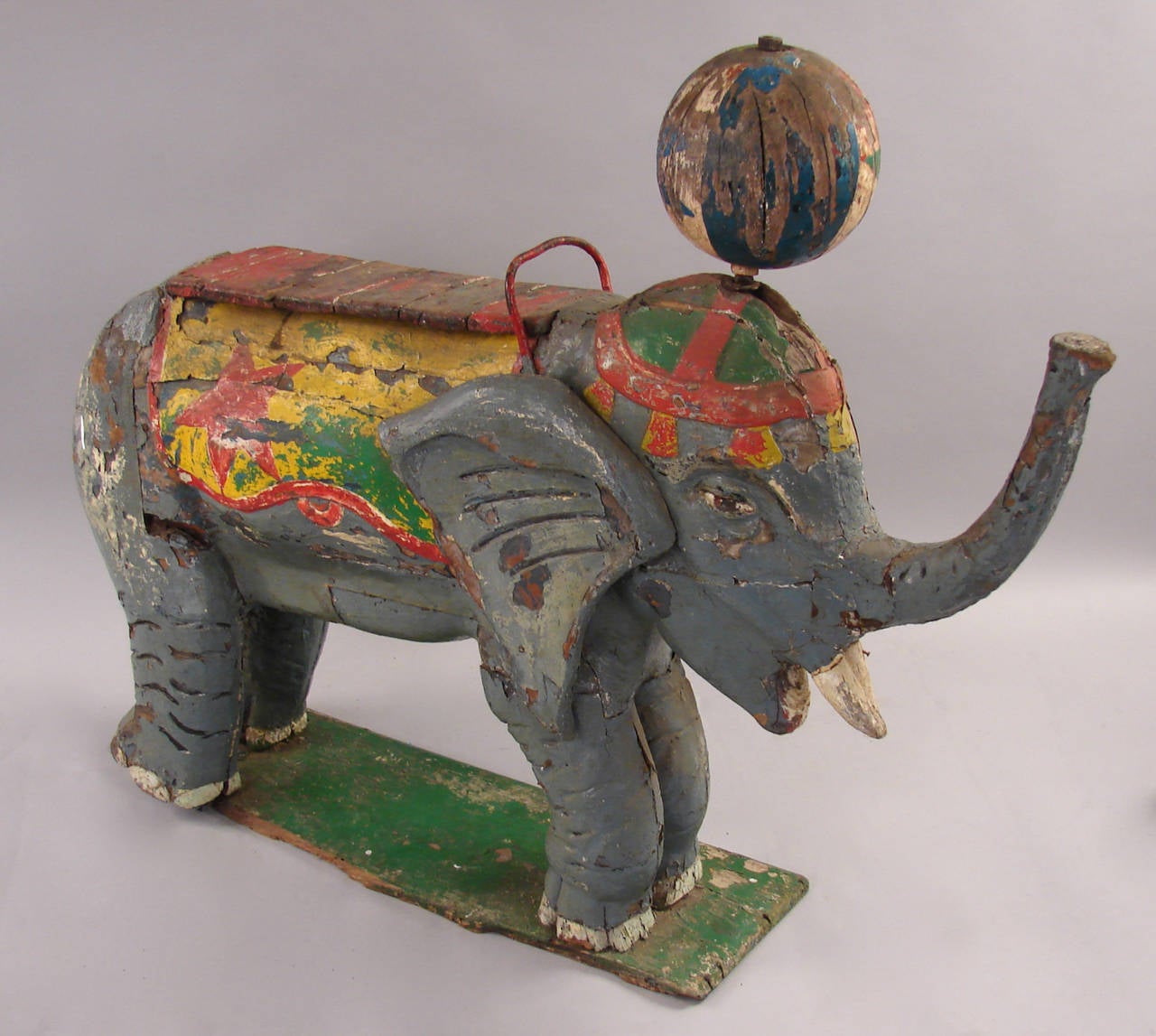 An amusing painted carved wood elephant with revolving sphere mounted to its head. Probably a carousel or circus figure of European or Indian origin.  Retains its original polychrome decoration,  circa 1900-1925.