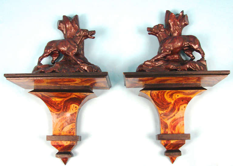 A good and very decorative pair of carved walnut dogs, probably Continental, in a naturalistic setting together with a contemporary pair of painted wall brackets.