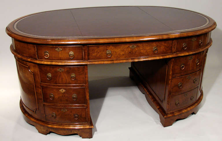 An attractive, good quality English oval figured walnut partners desk, the burgundy tooled leather top over three frieze drawers above six pedestal drawers ending in bracket feet. Reverse is configured in the same manner.