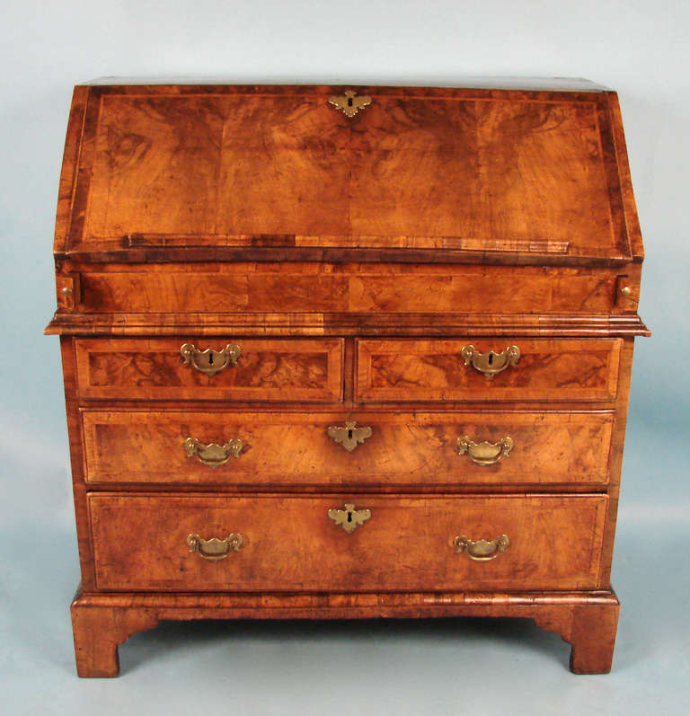 A fine English George II period walnut feather banded slant front desk having a rectangular top and slant front opening to a fitted interior with a well over two short and two long graduated drawers raised on original bracket feet. Excellent color