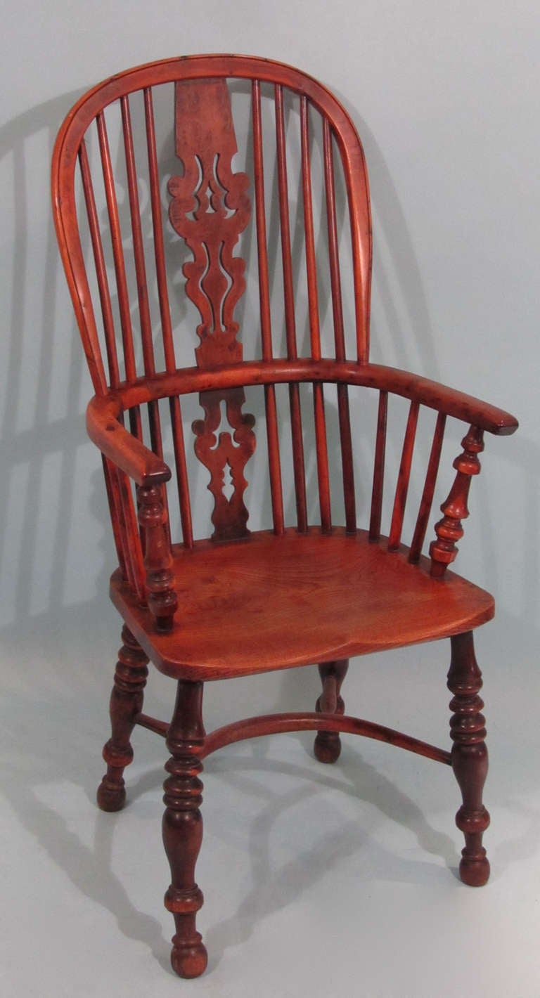 An English yew wood and elm high back Windsor arm chair, the wavy pierced back splat above a saddle seat over turned legs joined by a crinoline stretcher.  Circa 1850. Fine color and patina.