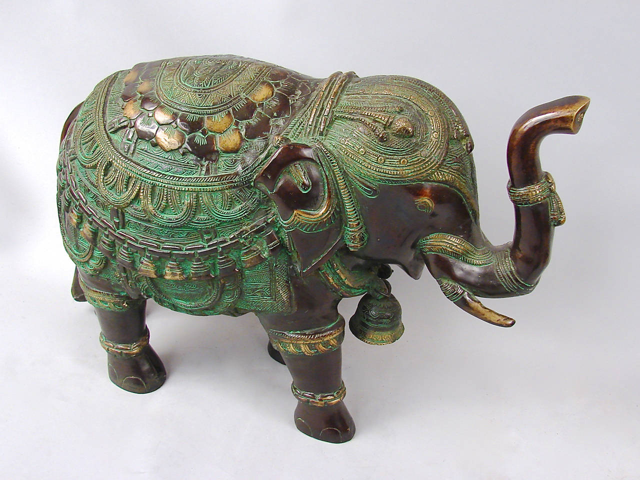 A decorative and pleasing pair of Indian cast bronze elephants, each with a bell around her neck, their trunks in the raised position, 20th century.