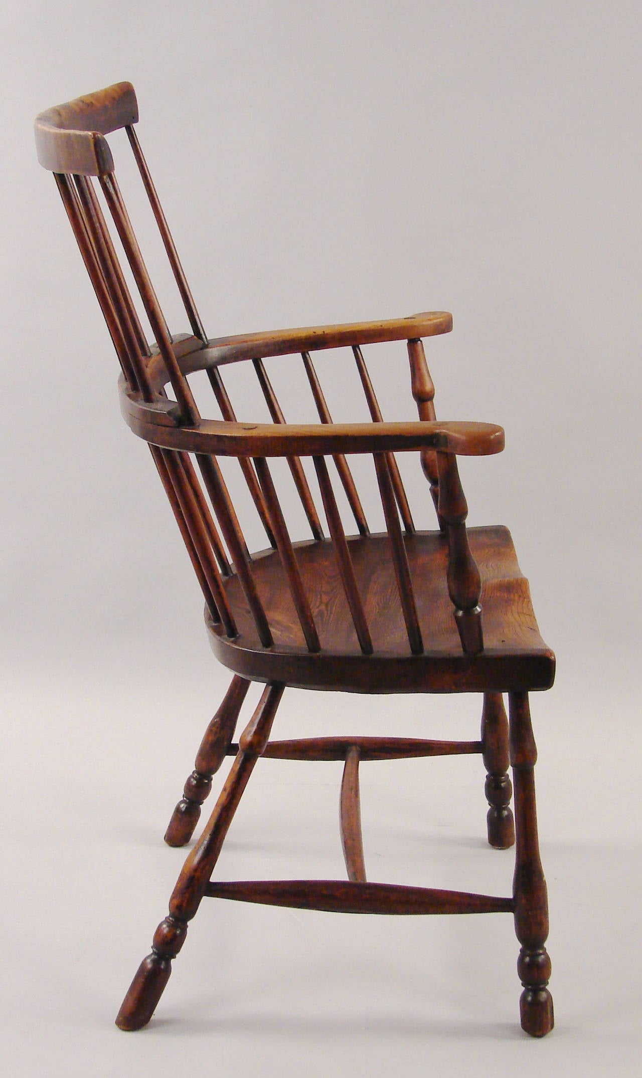 An English elm and hickory comb back windsor armchair, the spindle back meeting a well-shaped saddle seat supported on turned legs joined by a simple stretcher, circa 1820-1850. Lovely old color.