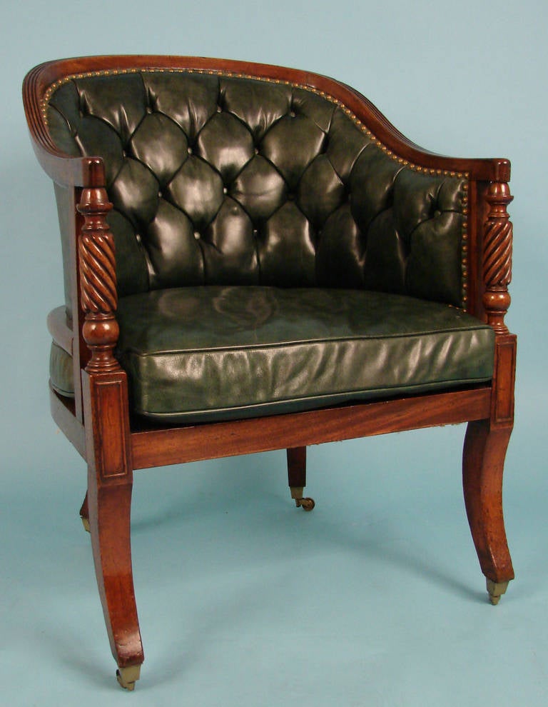A Regency mahogany tub bergere, the reeded toprail above a tufted leather upholstered back, the arms with rope turnings supported on front saber legs ending in casters. Circa 1820. Provenance: Kentshire.
