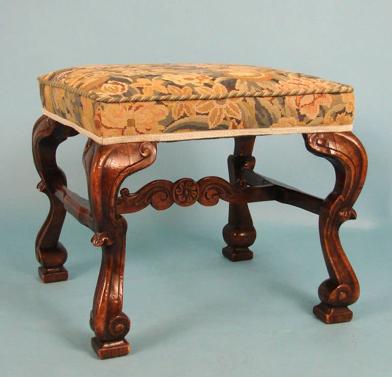 A fine English early 18th century walnut William and Mary  rectangular stool with a needlepoint upholstered seat.  Circa 1700.