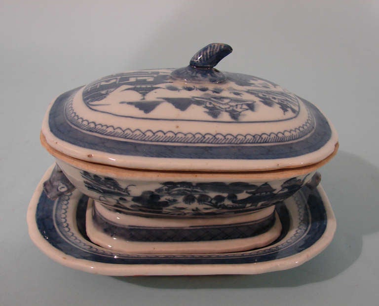 A Chinese blue and white Canton covered sauce tureen with under plate, the tureen with boar's head handles, decorated overall with river and garden scenes.  Circa 1860.