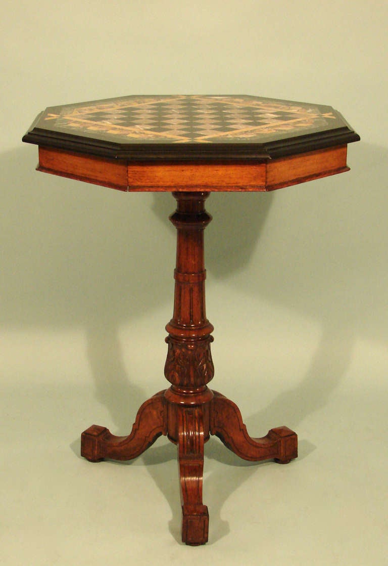 An attractive English specimen marble and oak games table, the chess board top inlaid with various types of Italian marble, the apron with one concealed drawer, supported by a turned standard ending in a tripod base.