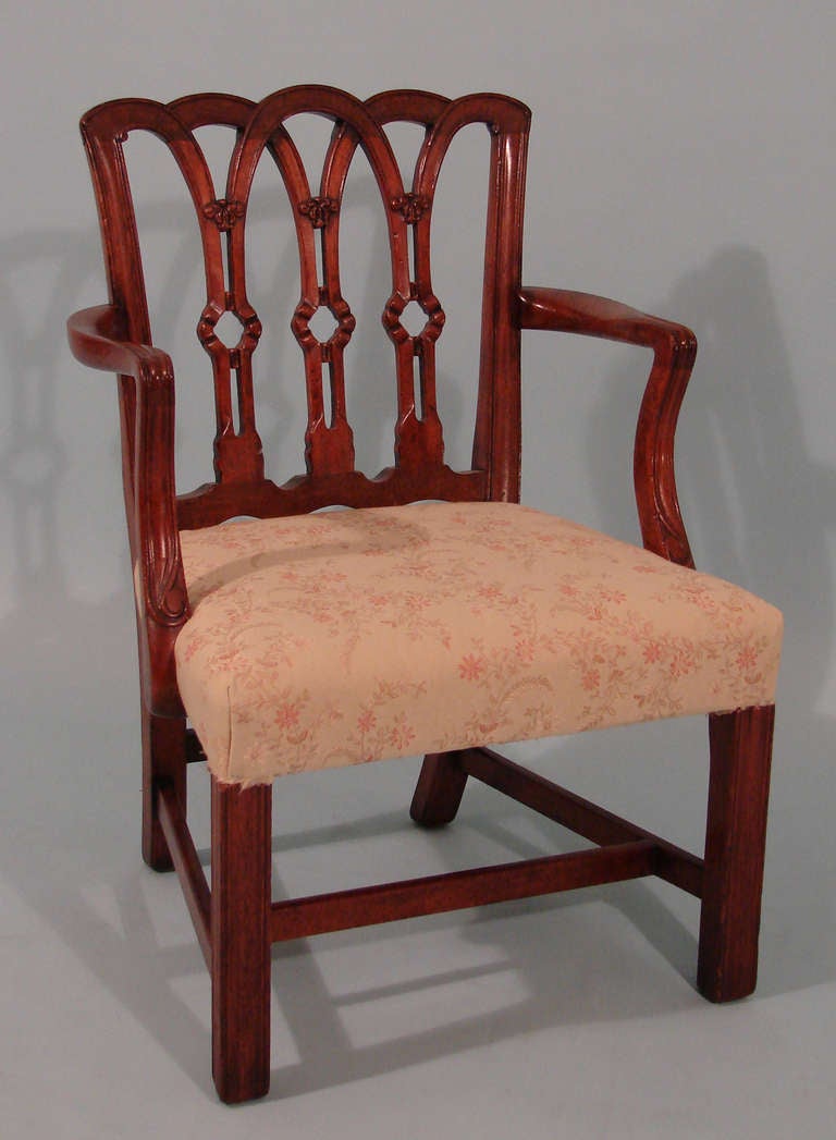 A charming English mahogany Chippendale style child's open arm chair, the back with ribbon motif, the molded legs joined by a box stretcher. Circa 1930.