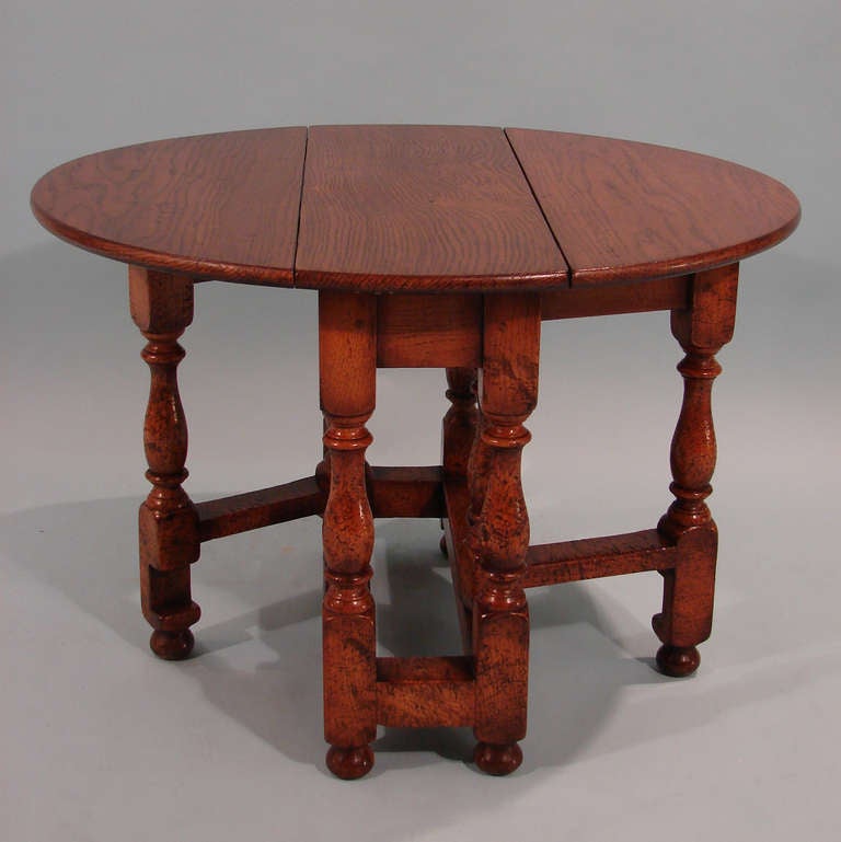 An English Jacobean style oak dropleaf table of small size, the 3 section top supported by turned gatelegs ending in small bun feet.