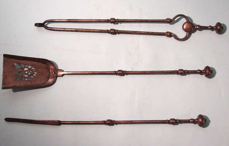 A  set of 3 English steel fire tools comprising a poker, pierced shovel and tongs, each piece with a turned handle. Circa 1840-1860.