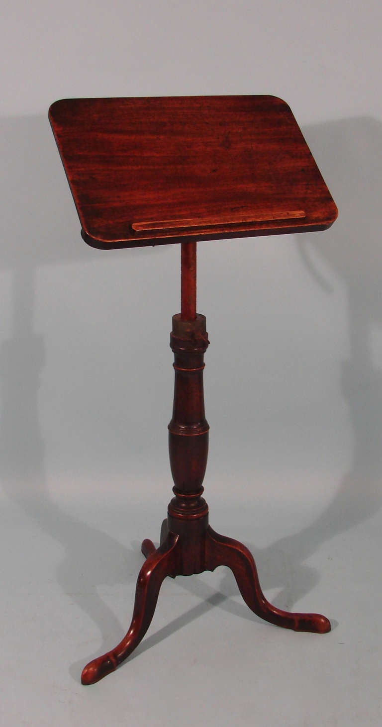 An English George III mahogany adjustable reading stand, the adjustable support with concealed book rest, supported by a tripod base on cabriole legs. Formerly with candle arms.