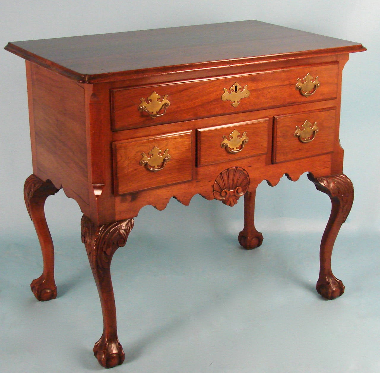 An American Chippendale style lowboy or dressing table, the overhanging top with notched corners above one long and three short drawers centered by a carved shell on a shaped apron, all supported on cabriole legs with carved knees terminating in
