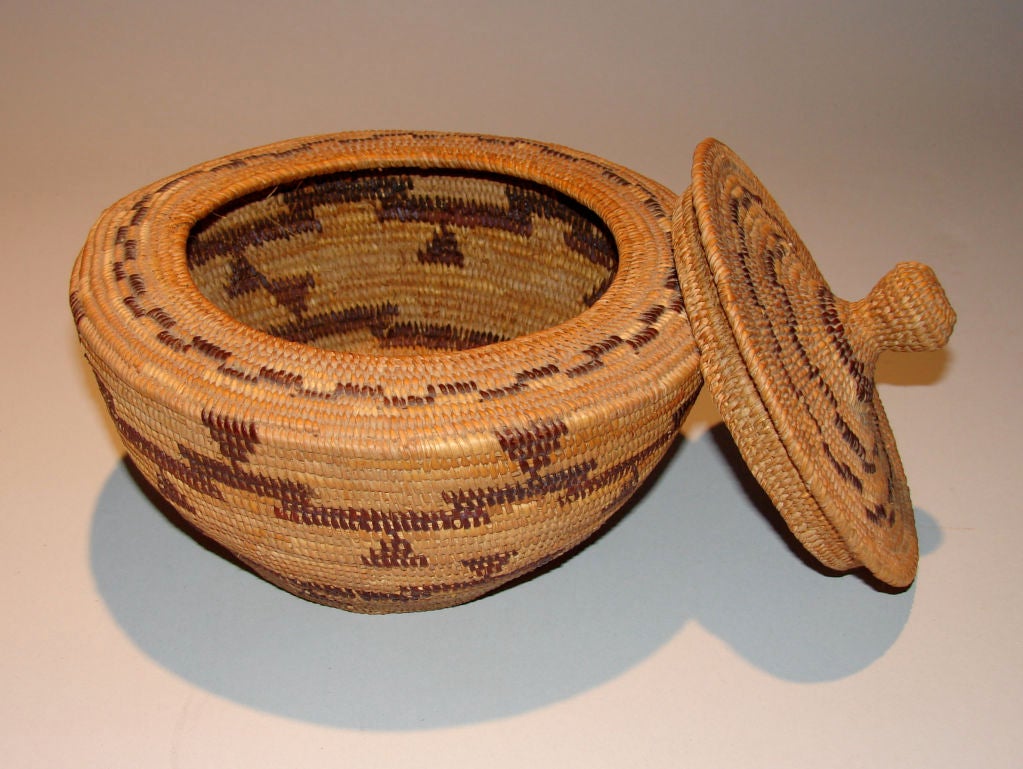 A Yokut bottle-neck lidded basket, 2 terraced bands with pendant triangles below the shoulder, concentric stepped designs encircling the lid.
