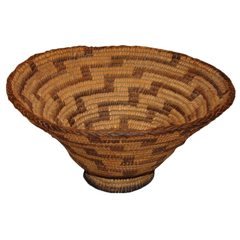 A Native American, possibly Yokut, woven basket with geometric design ending in a footed base.