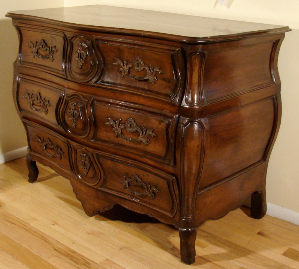 A substantial French Louis XV period provincial walnut bombe form three drawer commode, the drawers with carved details, with serpentine top, circa 1750. Probably Burgandy region.