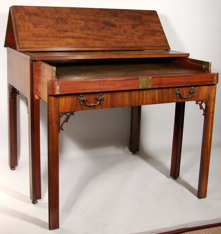 A George III mahogany architects desk

mid 18th century, the hinged rectangular top over a leather inset work surface and a pull out work surface, sliding to reveal divided wells and drawers raised on chamferred legs headed by scrolled brackets