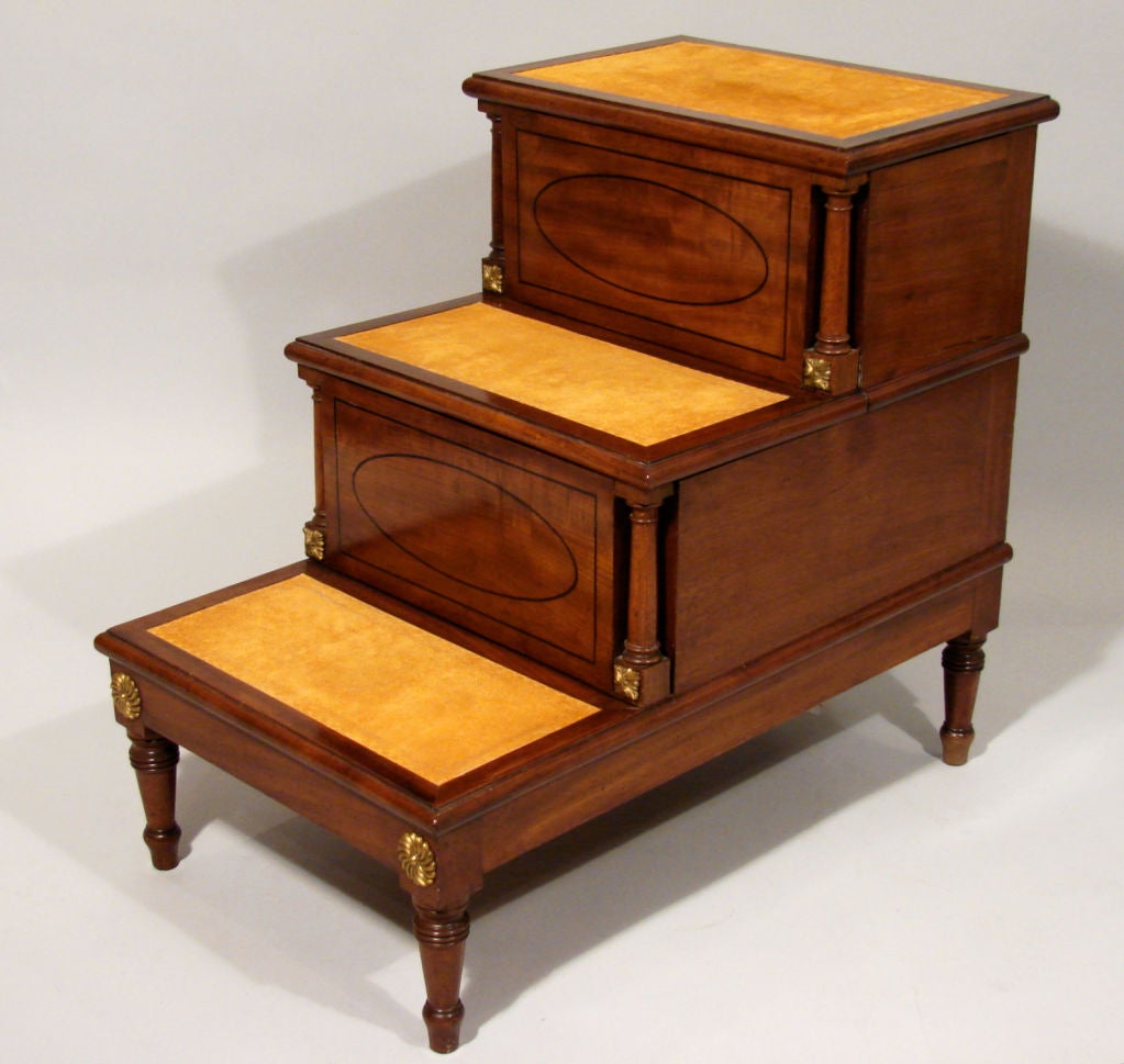 A pretty set of English inlaid mahogany library steps, the treads now lined in suede, the oval inlaid front panels flanked by gilt metal mounted  columnar supports over turned legs. Circa 1860.