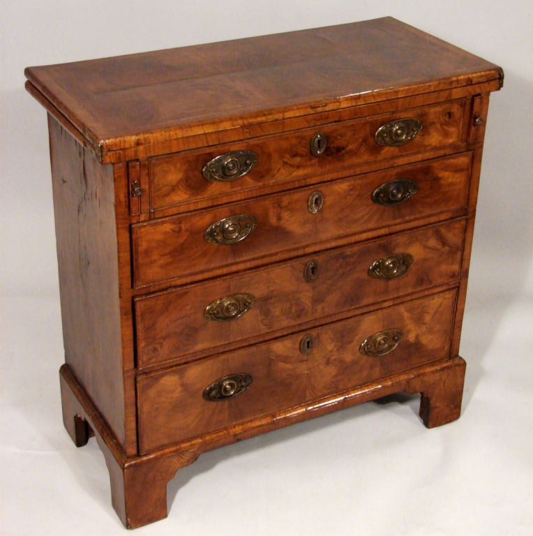 A George II period figured walnut bachelor's chest, the flip top with felt interior over 4 graduated drawers supported by high bracket feet. Hardware replaced.