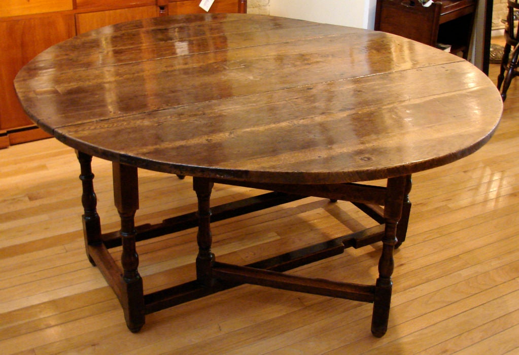 A large late 17th century English oak gateleg table, the circular top raised on well-turned legs joined by stretchers ending in bun feet circa 1680. Excellent color and patina.