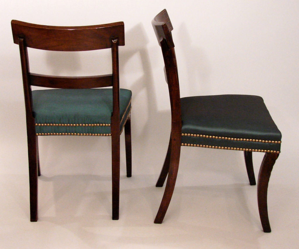 A fine set of 4 Regency mahogany sidechairs, the reeded backs with brass line inlay above reeded front saber legs with acanthus leaf carving. Circa 1810-1820.
Now upholstered in green silk with nail head trim.