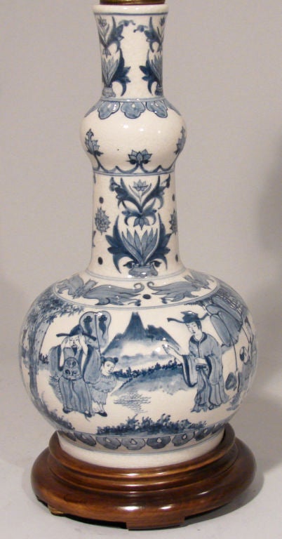 A nineteenth century Chinese blue Canton bottle form vase decorated overall with figures in a country landscape, resting on a wooden base. Now electrified.