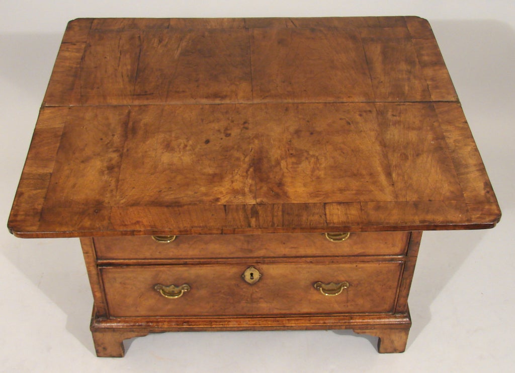 A good George I period walnut bachelor's chest, the folding cross and feather-banded top with moulded edge and cut corners above four graduated drawers on bracket feet. Attractive color.