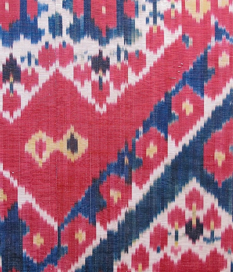 This is an authentic antique silk Ikat from Central Asia. Increasingly popularized today by fashion designers in Europe and New York, colorful abstract patterns are achieved within these textiles by intricately weaving patterns with selectively