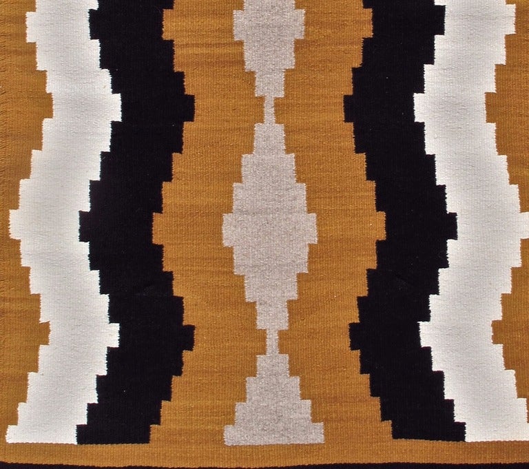 This simple small Navajo rug paints waves of natural ivory and brown to form subtle intimations of side-borders. A column of grey diamonds is drawn along the center of a camel-colored ground.  A classic Southwestern weaving! 