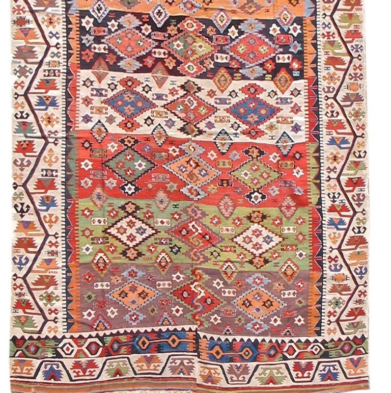 This delightful Kilim from eastern Anatolia makes use of a vivid palette of natural vegetal colors. Ivory borders with abstract meandering vine-scrolls frame a field of multicolored rows ornamented with geometric diamond design. Reyhanli kilims were