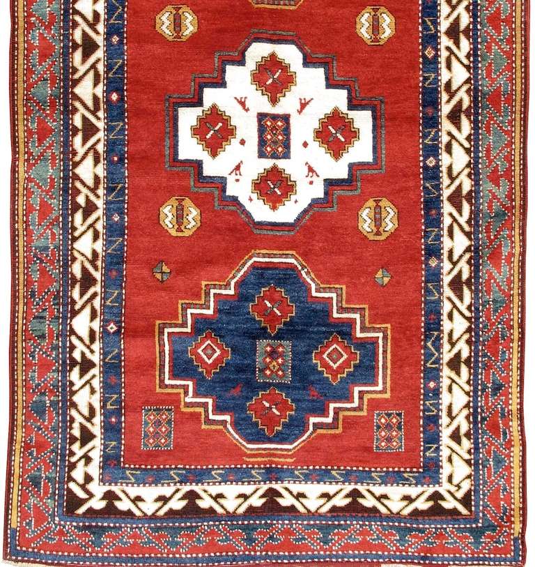 This large Borjalu prayer rug exemplifies the bold drawing, soft high pile and vivid colors that great Kazak rugs are known for. A column of three well spaced medallions float against a deep madder red ground. The inner workings of these medallions