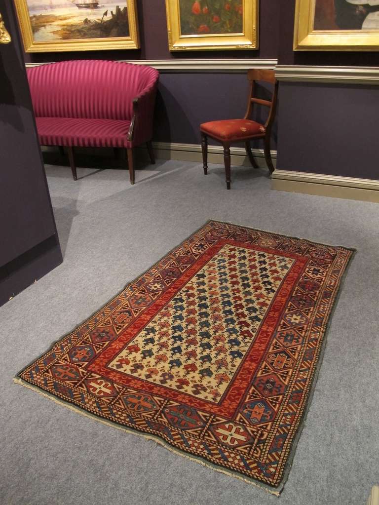 This pleasant South Caucasian Kuba rug draws stylized plants in diagonal, multicolored stripes across a white ground. The true green so prominent in this piece is a special feature, and it is paired well with contrasting tones of red derived from