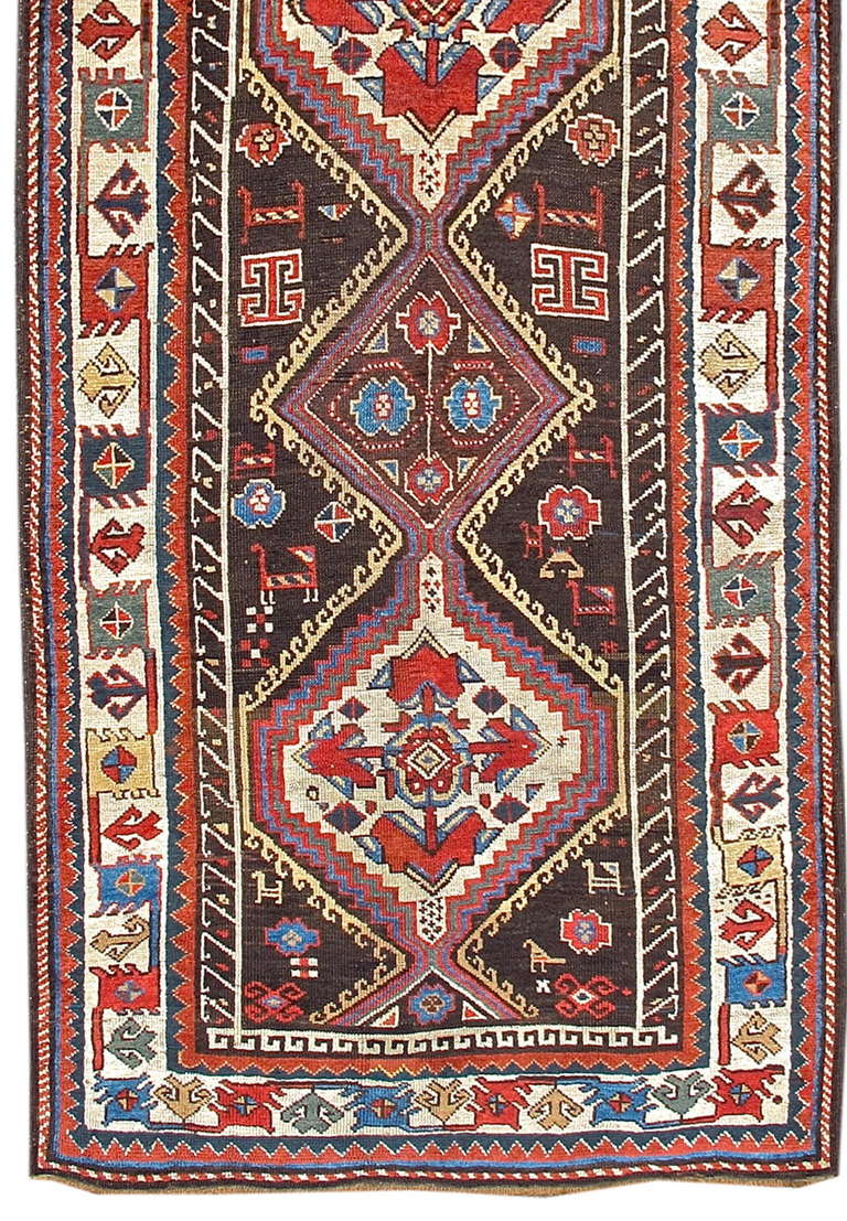 A wonderful folky five-medallion carpet with a chocolate brown field (switching occasionally to indigo blue) and enlivened by charming representations of animals and large flowers. The folksiness carries over to the simple but bold and
