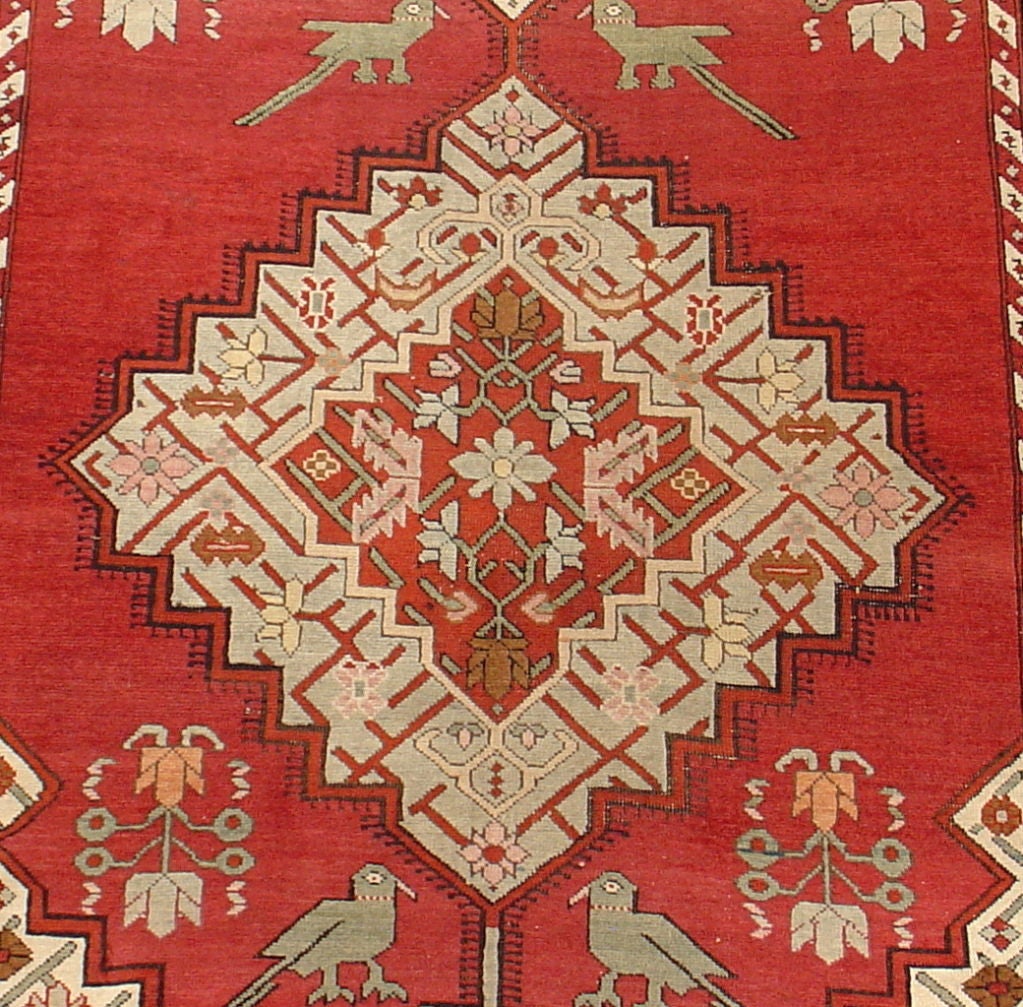 This pleasing Caucasian runner blends elements of more formal urban weavings with rustic charm. Ivory medallions are skillfully articulated on a relatively blank field accented with paired birds and vegetal forms. A simple border composed of two