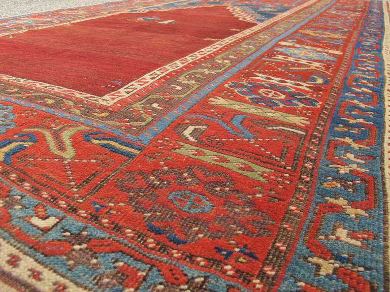 This classic Ladik prayer rug from central Anatolia draws a bold Mihrab accented by rams’ horn motif against a modulated madder-red ground. An assortment of classic Anatolian geometric elements float spaciously within the indigo blue spandrels as a