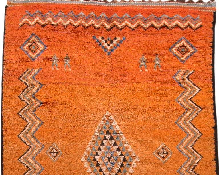 This early 20th century Moroccan rug blends formalism with minimalism. A diamond medallion composed entirely of stepped triangles floats in the center. Wave patterns on all four sides approximate borders while retaining their own independence and