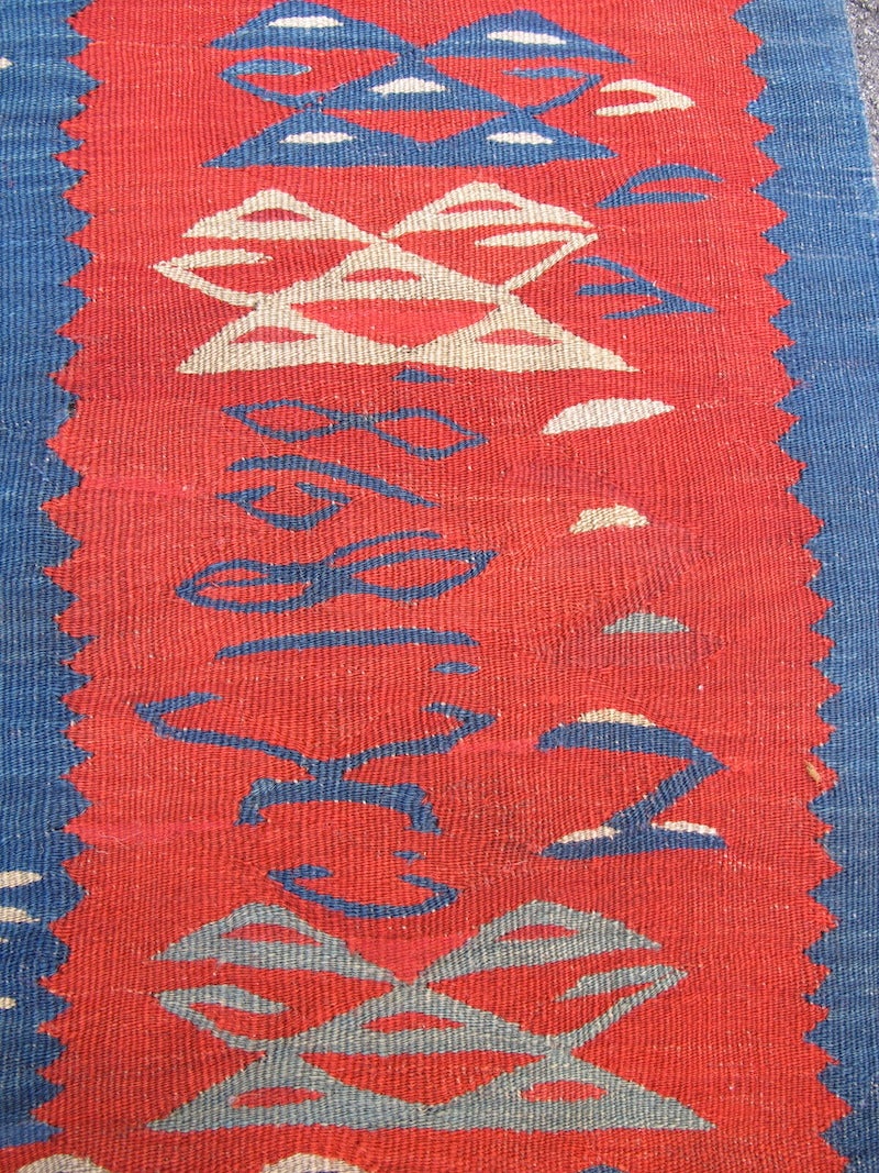 Woven with a sinuous tapestry weave, this Sarkoy Kilim from the Southeast Balkans paints a forest of green, blue, and ivory trees against a vibrant madder ground. Indeed, the prevalence of madder used in the field and border of this Kilim is both