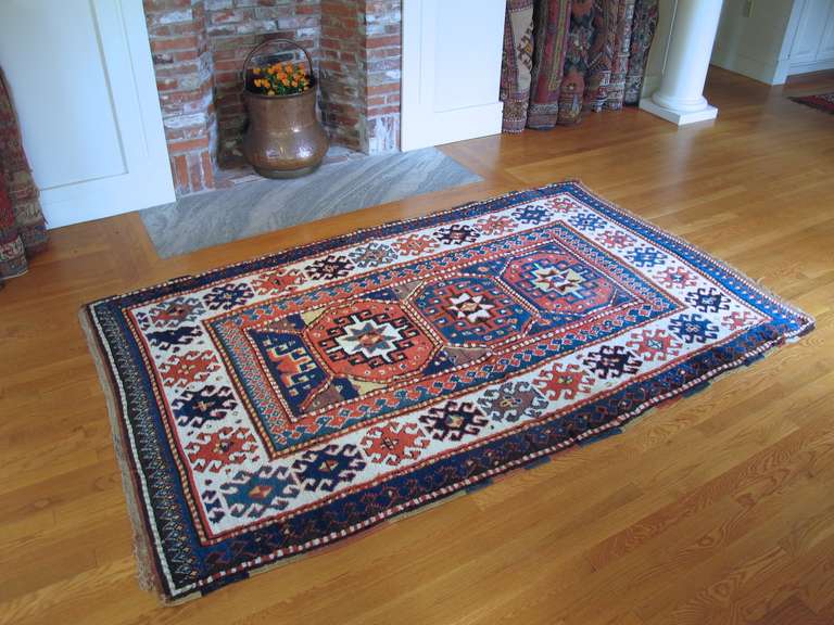 This Kazak rug was woven in the Caucasus in the late 19th century. Bold drawing exemplified by three octagonal medallions and a stepped geometric border is accented by equally bold color. The quality of the madder derived red is particularly