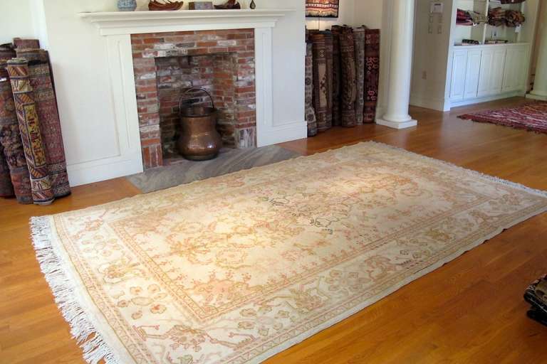 This beautiful small room size Oushak is woven with the characteristically soft wool and classic pale coloration that makes these antique Anatolian rugs favorites with decorators. The same buttery hues of ivory, rose and ocher are used throughout