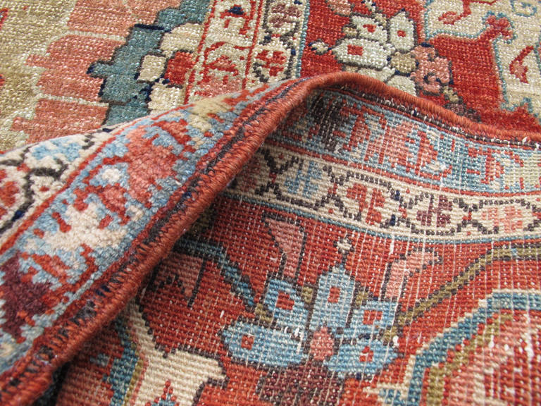 Heriz carpets are frequently known for their spectacular medallions and related corner-pieces drawn with graphic boldness. This piece unusually but quite pleasantly takes an alternate approach. A small red medallion, almost more of a rosette or a