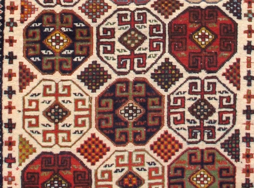 This ivory ground Kuba rug from the south Caucasus uses an over-all field design of octagonal shield ornament. This motif is seen often in, and may derive from, sumac technique design from smaller bags that were also woven in the region. Its