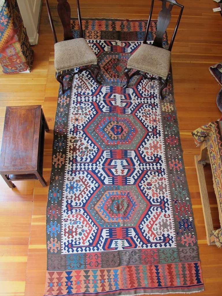 This monumental Anatolian Kilim blends vivid saturated color with bold drawing and a keen sense of negative space. Woven on a narrow village loom in two halves and then joined together, the white of the field provides a perfect canvas for a central