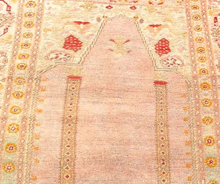 Soft wool and a soft palette join in this lovely niched Oushak prayer rug from western Anatolia. The columns and spandrels as well as the palmette and leaf pattern of the border all trace to prayer rug design of the Kula Transylvanian type of the