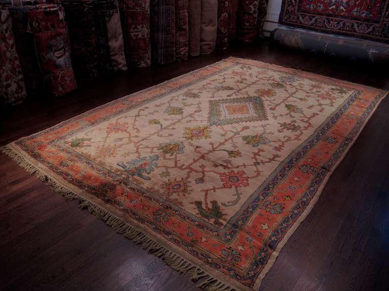 A soft color palette including accents of light blue, peach and spring green against a cream ground, is matched by lush and equally soft wool in this turn-of-the-century Oushak carpet from western Anatolia. Large-scale persianate ornament is drawn