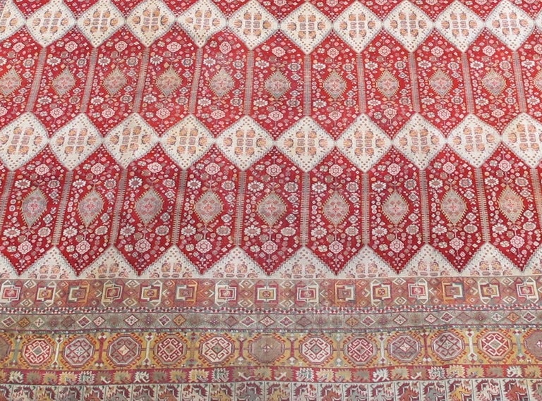 Cet élégant tapis surdimensionné du nord de l'Inde fait tourner des rangées d'hexagones rouge rubis avec des diamants blancs scintillants. Ces teintes semblables à des bijoux, associées à la précision de l'exécution et à une grande attention portée