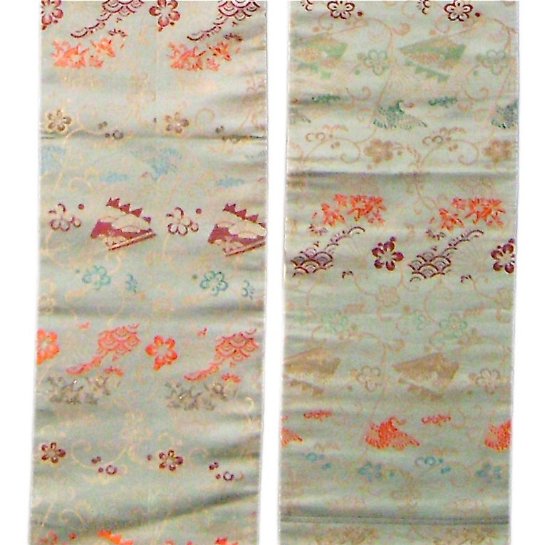 A silk Obi sash in soft celadon green, decorated with floral elements.