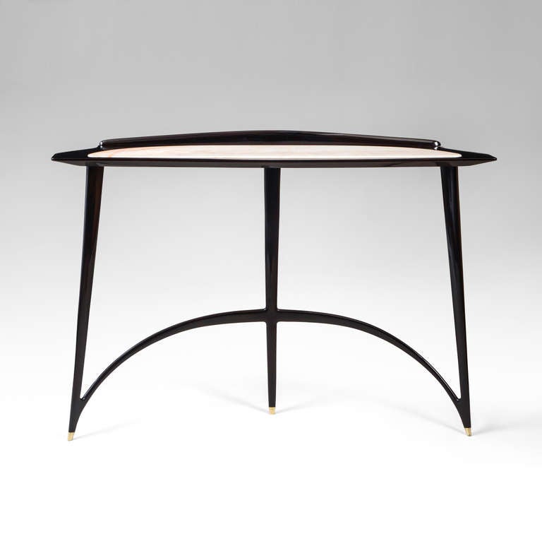 Displaying minimal, yet graceful beauty that suggests greater volume than what truly exists.  The  back gallery flowing into a curvaceous top with inset marble, raised on three tapering legs connected by an expressively arched stretcher, terminating
